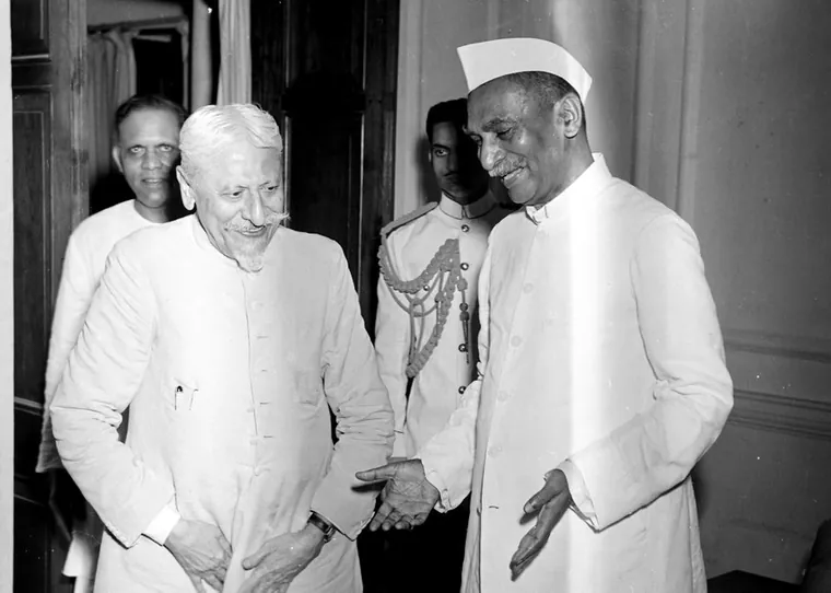 Maulana Abul Kalam Azad and Dr Rajendra Prasad talking indoors, both smiling and dressed in white.